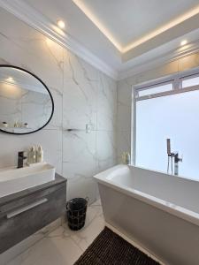 White Cottage Boutique Guesthouse في سواكوبموند: حمام أبيض مع حوض ومرآة +10 صور