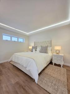 White Cottage Boutique Guesthouse في سواكوبموند: غرفة نوم بيضاء مع سرير كبير وسجادة