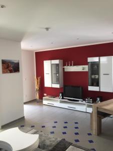 sala de estar con pared roja y TV en Ferienhaus Brueckner, en Mörstadt