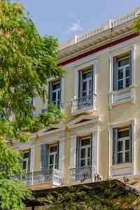 SoHo Athinas 60 في أثينا: مبنى اصفر كبير به بلكونات واشجار