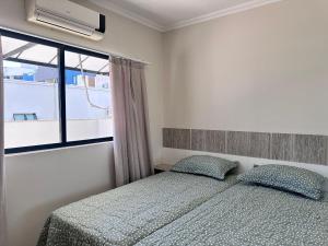 Un dormitorio con una cama y una ventana en B484 - Apto 3 quartos perto do mar e com vista., en Bombas