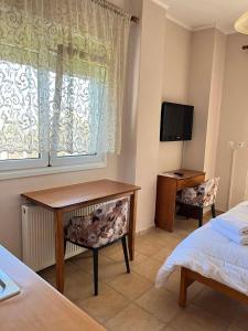 a bedroom with a desk and a bed and a television at Drosia Hotel in Kato Loutraki +42 photos