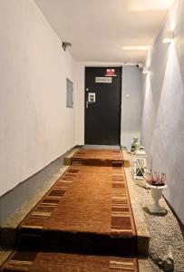 a hallway with a black door and a wooden floor at Alcorso Pension in Banská Bystrica