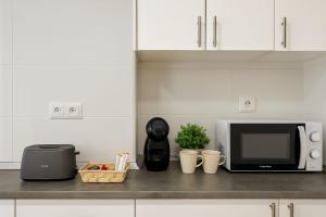a kitchen counter with a microwave oven and a counter top with cups at Apartamentos Benalua Alicante - Con Parking - Elegir en el momento de la reserva in Alicante