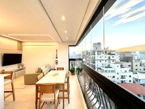 B258 - Apto de luxo com vista mar em Bombinhas في بومباس: شرفة مع طاولة وكراسي ونافذة كبيرة