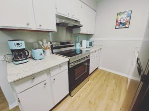 a kitchen with white cabinets and a black stove top oven at White Sand Getaway steps from Beach in Gulfport