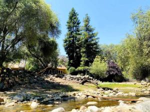 a river with rocks and a house in the background at Sequoia Cabin by the River in Three Rivers