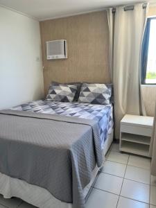 a bedroom with a bed with a blue and white blanket at Residencial Neo 1 in Maceió