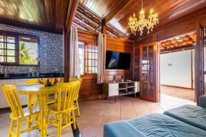 een woonkamer met een tafel, stoelen en een televisie bij Aconchego in Mangaratiba