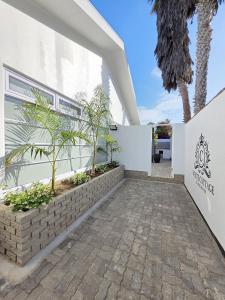 White Cottage Boutique Guesthouse في سواكوبموند: ممشى يؤدي الى واجهة مبنى ابيض
