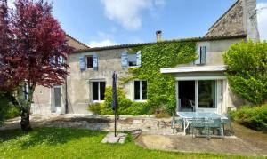 a house with a picnic table in front of it at Maison Charentaise 12 à 14 personnes in Sémussac
