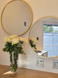 un vaso di fiori su un tavolo di fronte a uno specchio di White Cottage Guesthouse a Swakopmund