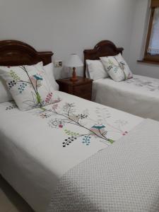 Dos camas con sábanas blancas con pájaros pintados en ellas. en Apartamento El Fondon 1, en Cangas de Onís