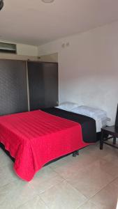 een groot bed met een rode deken erop bij Hotel EL QUIMBO in Garzón +4 foto's