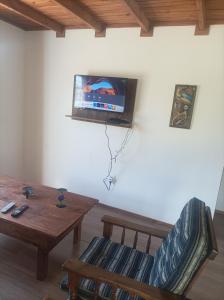 ein Wohnzimmer mit einem Tisch und einem TV an der Wand in der Unterkunft Cabaña Punta del Diablo in Punta Del Diablo