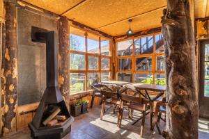 a dining room with a fireplace and a table at Pucón REC-Lodge Cabañas Las Bandurrias in Pucón