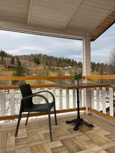 ein Schreibtisch auf einer Veranda mit einem Stuhl und einem Fenster in der Unterkunft Сироварня Далекі Гори in Snidavka