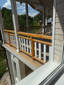 Un porche con barandillas de madera en una casa. en Сироварня Далекі Гори, en Snidavka
