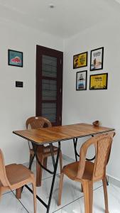 una mesa de madera con sillas y cuadros en la pared en Roameo, Varkala - A Cowork by The Hostel Stories, en Varkala
