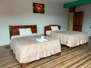 a hotel room with two beds and a candle on a table at Hotel PRADO'S in Satipo +5 photos