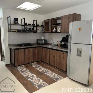 Espectacular apto cerca a la Zona Rosa في سانتا روزا دي كابال: مطبخ مع ثلاجة بيضاء وخزائن خشبية