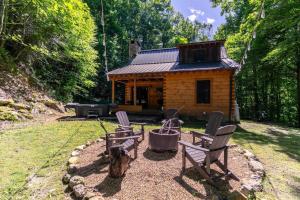 una baita con due sedie e un cane seduto di fronte di Whiskey Creek Cabin a Beech Mountain