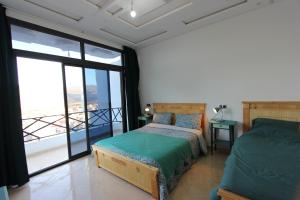 a bedroom with two beds and a balcony at Agadir Funky Chill Guesthouse Surf, Horse, Music adventures in Aourir