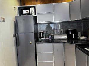 a kitchen with white cabinets and a refrigerator at Alshuruq Stay in Al Ḩamrāʼ