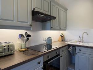 a kitchen with white cabinets and a counter top at The Cottage in Keswick