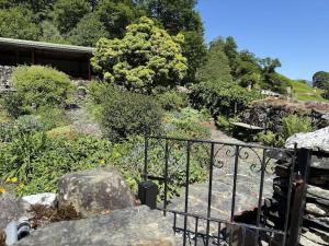 a garden with a gate and rocks and trees at The Cottage in Keswick