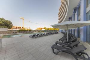 a row of chairs and an umbrella on a building at B42 - Oceano Atlantico Apartment in Portimão