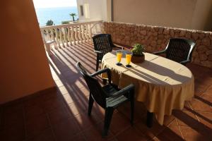 a table with chairs and drinks on a balcony at Utković Beachfront Apartments in Vrsi