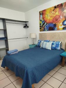 a bedroom with a blue bed and a painting on the wall at Habitación privada en casa de huespedes in Guadalajara