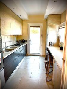 a kitchen with wooden cabinets and a sink and a door at Villa Lenuska in Quartu SantʼElena