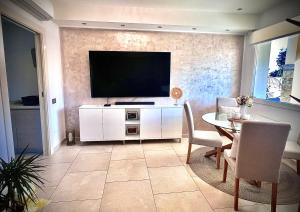a living room with a television and a table with chairs at Villa Lenuska in Quartu SantʼElena