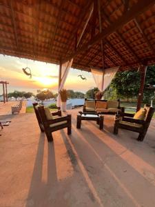 a group of chairs sitting under a pavilion with the sunset at Pousada e Restaurante Cajutuba in Belterra +14 photos