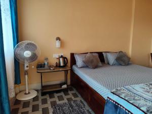 um quarto com uma cama, uma ventoinha e uma mesa em Arara ibt homestay em Cherrapunji