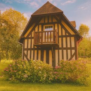 a black and white building with a balcony at Le Hameau des Prés-Verts, un séjour détente et bien être pour les amoureux de la nature au cœur du Pays d'Auge, en Normandie in Les Champeaux