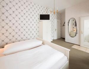 Schlafzimmer mit einem weißen Bett und einem Spiegel in der Unterkunft Hotel Haus Müller in Marburg an der Lahn