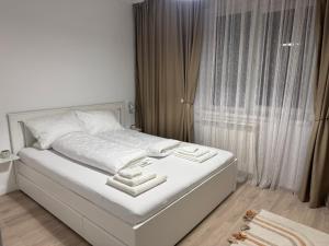 un letto bianco in una camera da letto con finestra di Zen apartments a Craiova Altre 3 foto