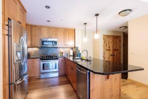 a kitchen with stainless steel appliances and wooden cabinets at Spring Creek Serenity at Rundle Cliffs Lodge in Canmore