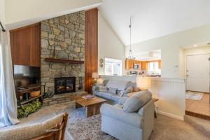 een woonkamer met 2 banken en een stenen open haard bij Chetola: Chestnut 8 in Blowing Rock