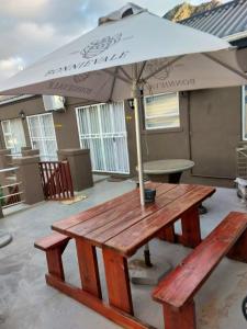 a picnic table with an umbrella on a patio at Fijnbos - Something-Els in Rooiels