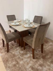 einen Esstisch mit Stühlen und einen Tisch mit Tellern in der Unterkunft Regency Loft 02 in Petrolina + 7 Fotos