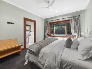 a bedroom with a large bed and a window at Le Chateau Moderne - Cedar Barrel Sauna & Spa in Tamahere