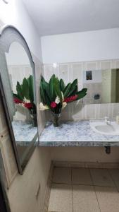 un bagno con lavandino e un vaso di fiori su un bancone di Guatiguara Dónde Orlando a Buritaca