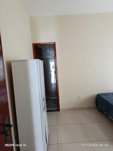 een witte koelkast in een kamer met een spiegel bij Josy House in Cabo Frio