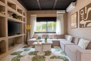 Una sala de estar con un sofá y un televisor en Villa Riad Private heated Pool with breakfast, en Marrakech