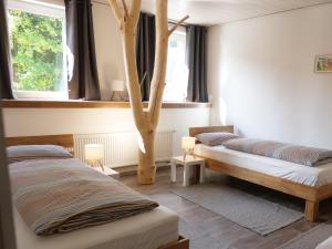 a bedroom with two beds and a tree in it at Albsteig-Apartments Gruibingen in Gruibingen