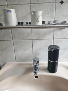 a bathroom sink with a cup and a toothbrush at Ferienwohnung Harzgefühl in Elbingerode +19 photos